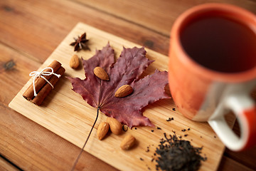 Image showing cup of tea, maple leaf and almond on wooden board