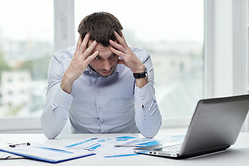 Image showing stressed businessman with laptop at office