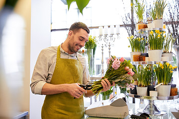 Image showing smiling florist man making bunch at flower shop