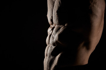 Image showing torso of attractive male body builder on black background.