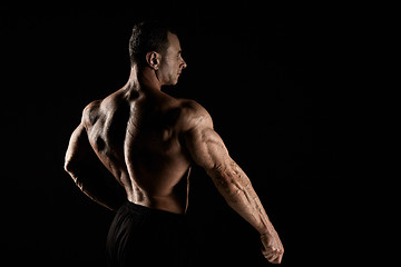 Image showing torso of attractive male body builder on black background.