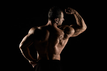 Image showing torso of attractive male body builder on black background.