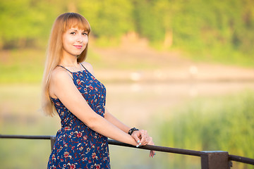 Image showing The charming young girl standing on a rustic bridge at dawn sun