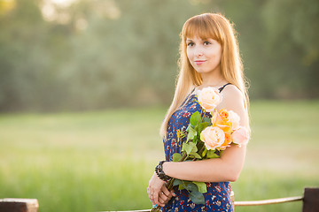 Image showing Beautiful girl standing on a river bridge with a bouquet of flowers. Portrait