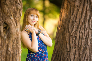 Image showing Happy young beautiful girl standing between two trees