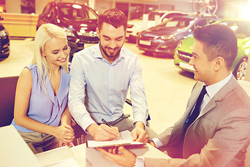 Image showing happy couple with car dealer in auto show or salon