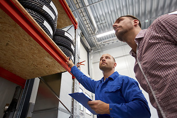 Image showing auto mechanic and man with tires at car shop