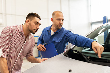 Image showing auto mechanic with clipboard and man at car shop