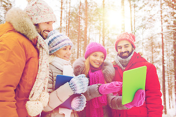 Image showing smiling friends with tablet pc in winter forest