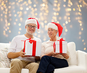 Image showing happy senior couple in santa hats with gift boxes