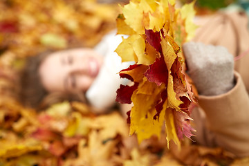 Image showing close up of happy woman lying on autumn leaves