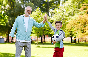 Image showing old man and boy with soccer ball making high five