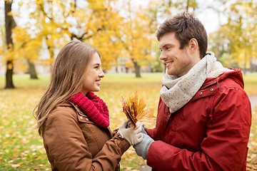 Image showing happy couple with maple leaves in autumn park