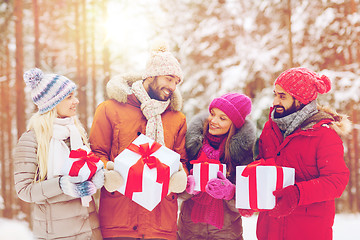 Image showing happy friends with gift boxes in winter forest