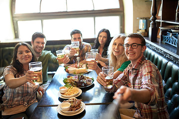 Image showing happy friends with selfie stick at bar or pub