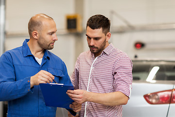 Image showing auto mechanic with clipboard and man at car shop