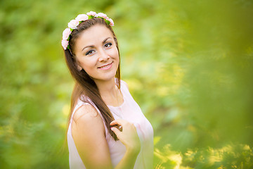 Image showing Portrait of a young beautiful girl on a blurred background of green foliage