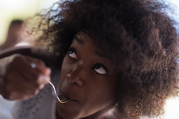 Image showing a young African American woman eating pasta