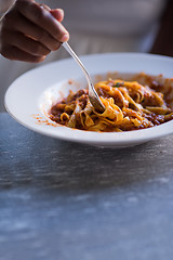 Image showing a young African American woman eating pasta