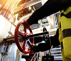 Image showing factory worker turning valve