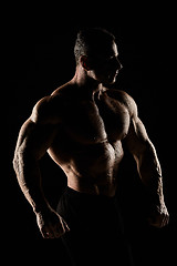 Image showing torso of attractive male body builder on black background.