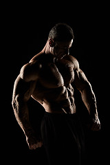 Image showing torso of attractive male body builder on black background.