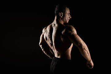 Image showing torso of attractive male body builder on black background.