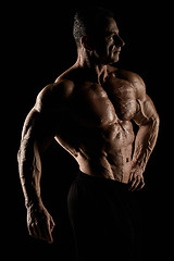 Image showing torso of attractive male body builder on black background.