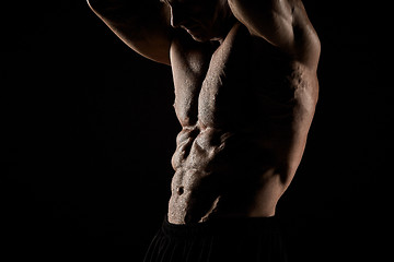 Image showing torso of attractive male body builder on black background.