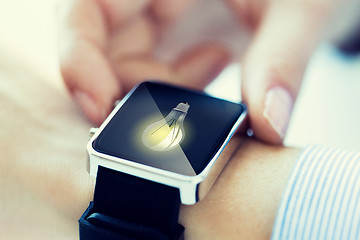 Image showing close up of hands with lightbulb on smartwatch