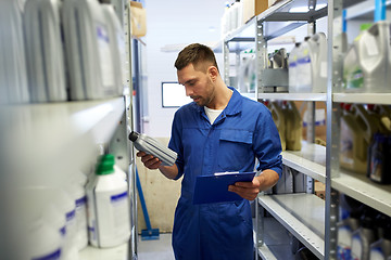 Image showing auto mechanic with oil and clipboard at car shop