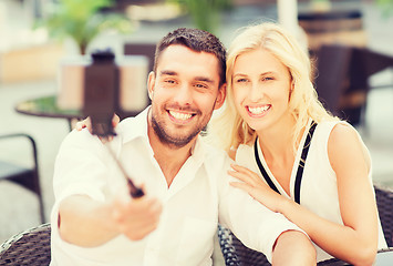 Image showing happy couple taking selfie with smartphone at cafe