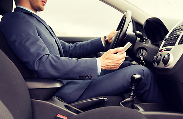 Image showing close up of man with smartphone driving car