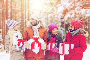 Image showing happy friends with gift boxes in winter forest