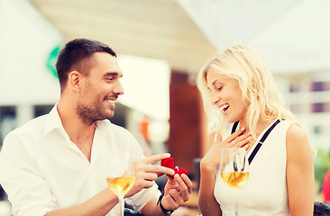 Image showing happy couple with engagement ring and wine at cafe