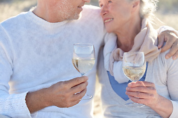 Image showing happy senior couple drinking wine on summer beach