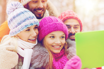 Image showing smiling friends with tablet pc in winter forest