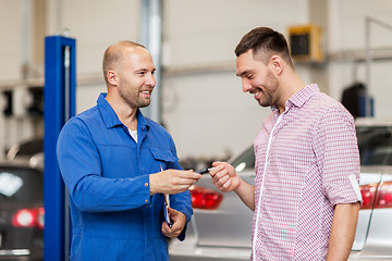 Image showing auto mechanic giving key to man at car shop