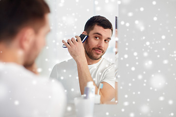 Image showing man shaving beard with trimmer at bathroom