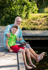 Image showing grandfather and boy with tablet pc on river berth