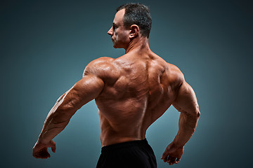 Image showing torso of attractive male body builder on gray background.