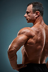 Image showing torso of attractive male body builder on gray background.