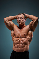 Image showing torso of attractive male body builder on gray background.