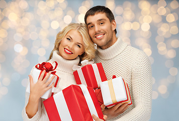 Image showing happy couple with christmas gifts over lights