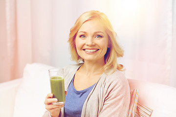 Image showing happy woman drinking green juice or shake at home