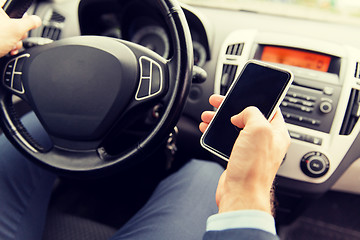 Image showing close up of man hand with smartphone driving car