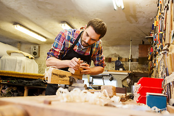 Image showing carpenter working with plane and wood at workshop