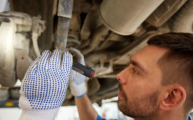 Image showing mechanic man with flashlight repairing car at shop