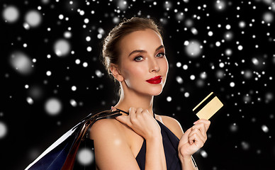 Image showing woman with credit card and shopping bags over snow