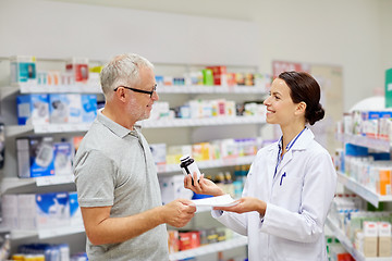 Image showing pharmacist and senior man buying drug at pharmacy